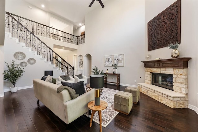 201 Montalcino Blvd, Austin, TX 78734 - living area featuring arched walkways, dark wood-style floors, stairs, a fireplace, and a towering ceiling