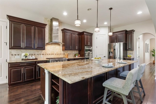 201 Montalcino Blvd, Austin, TX 78734 - kitchen with stainless steel appliances, wall chimney exhaust hood, arched walkways, dark wood-type flooring, and dark brown cabinets