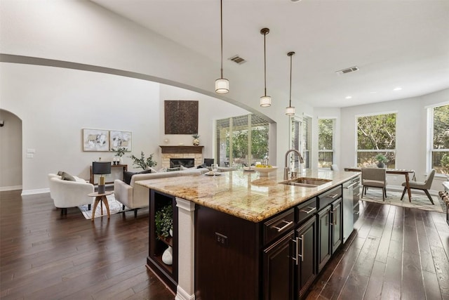 201 Montalcino Blvd, Austin, TX 78734 - kitchen featuring arched walkways, dark wood-type flooring, stainless steel dishwasher, a fireplace, and light stone counters