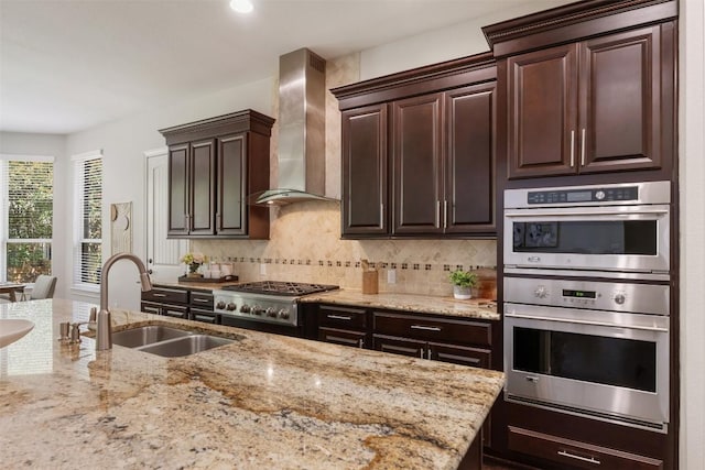 201 Montalcino Blvd, Austin, TX 78734 - kitchen featuring wall chimney range hood, stainless steel appliances, light stone counters, dark brown cabinets, and decorative backsplash