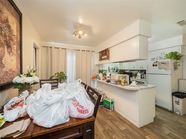 8508 Dryfield Dr, Austin, TX 78758 - kitchen with freestanding refrigerator, a peninsula, wood finished floors, and light countertops