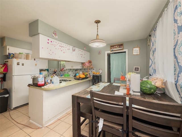 8508 Dryfield Dr, Austin, TX 78758 - kitchen with freestanding refrigerator, a peninsula, light tile patterned floors, white cabinetry, and tasteful backsplash