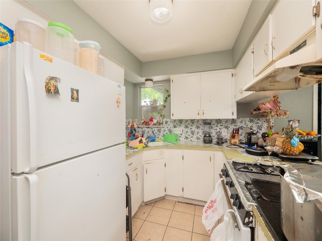 8508 Dryfield Dr, Austin, TX 78758 - kitchen with freestanding refrigerator, under cabinet range hood, stove, light tile patterned floors, and white cabinetry
