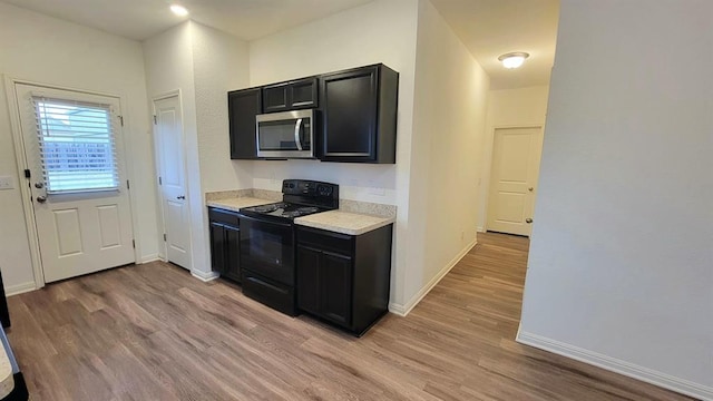 850 Bunton Reserve Blvd, Kyle, TX 78640 - kitchen with black electric range oven, stainless steel microwave, dark cabinets, light countertops, and light wood-type flooring