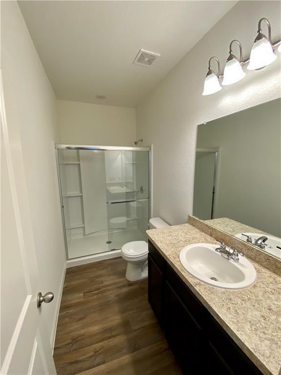 850 Bunton Reserve Blvd, Kyle, TX 78640 - bathroom with wood finished floors, vanity, and a stall shower