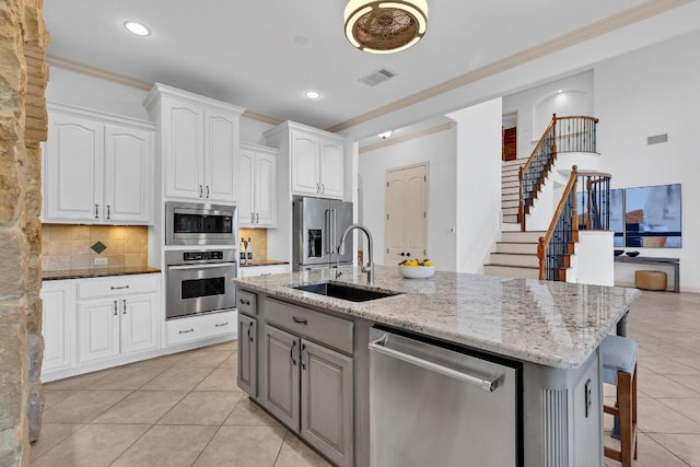 14417 Heron Bay Cv, Bee Cave, TX 78738 - kitchen featuring stainless steel appliances, light tile patterned flooring, crown molding, white cabinets, and light stone countertops