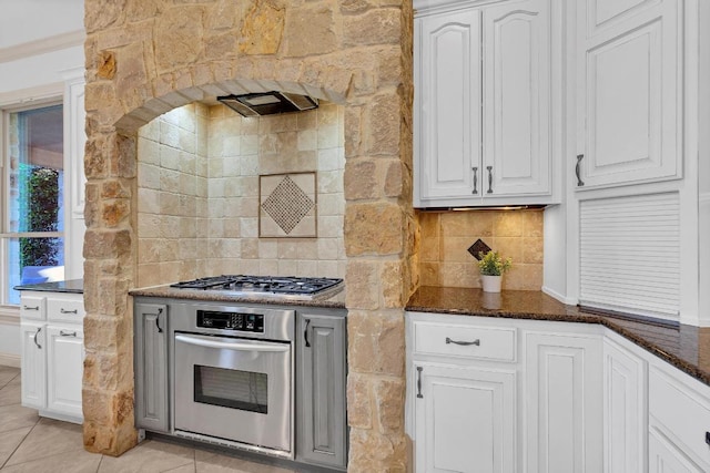 14417 Heron Bay Cv, Bee Cave, TX 78738 - kitchen with appliances with stainless steel finishes, white cabinetry, tasteful backsplash, and dark stone counters
