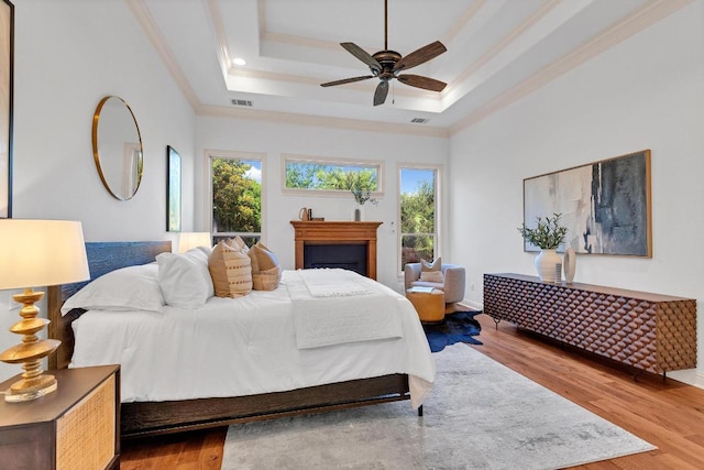 14417 Heron Bay Cv, Bee Cave, TX 78738 - bedroom featuring multiple windows, ornamental molding, wood finished floors, a raised ceiling, and a ceiling fan