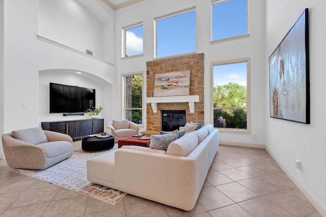 14417 Heron Bay Cv, Bee Cave, TX 78738 - living area featuring light tile patterned flooring, healthy amount of natural light, a stone fireplace, and a high ceiling