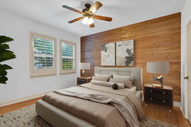14417 Heron Bay Cv, Bee Cave, TX 78738 - bedroom with wooden walls, an accent wall, wood finished floors, and ceiling fan