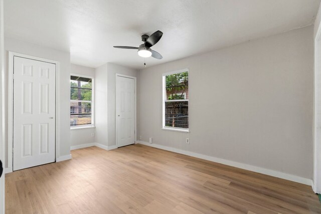 1040 Rosemont St, Austin, TX 78723 - unfurnished bedroom with light wood-style floors, multiple windows, two closets, and ceiling fan