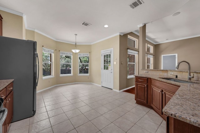 202 Muscovy Ln, Cedar Park, TX 78613 - kitchen featuring freestanding refrigerator, light tile patterned floors, crown molding, hanging light fixtures, and light stone countertops