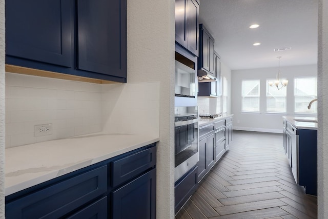 2321 Clear Pond Vw, Leander, TX 78641 - kitchen with stainless steel appliances, blue cabinets, a chandelier, recessed lighting, and pendant lighting