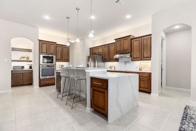 2707 Saint Paul Rivera Ln, Round Rock, TX 78665 - kitchen with appliances with stainless steel finishes, arched walkways, light countertops, hanging light fixtures, and recessed lighting