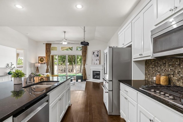 14016 Tyburn Trl, Austin, TX 78717 - kitchen with appliances with stainless steel finishes, tasteful backsplash, a glass covered fireplace, ceiling fan, and white cabinets
