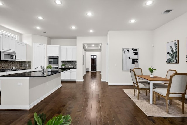 14016 Tyburn Trl, Austin, TX 78717 - kitchen with appliances with stainless steel finishes, dark countertops, dark wood finished floors, decorative backsplash, and recessed lighting