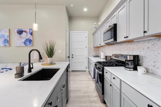 7215 Bennett Ave, Austin, TX 78752 - kitchen with stainless steel appliances, light wood-type flooring, tasteful backsplash, light stone counters, and pendant lighting