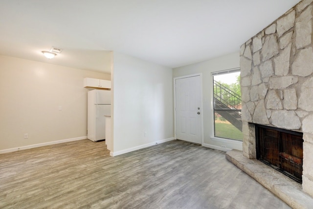 4307 S 1st St Unit 103, Austin, TX 78745 - unfurnished living room featuring light wood-style floors and a stone fireplace