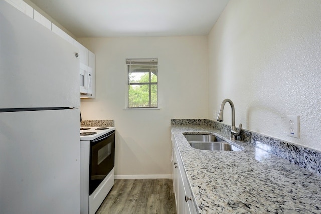 4307 S 1st St Unit 103, Austin, TX 78745 - kitchen featuring white appliances, white cabinetry, light wood finished floors, and light stone countertops