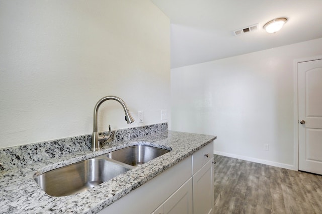 4307 S 1st St Unit 103, Austin, TX 78745 - kitchen with light wood-type flooring, light stone countertops, and white cabinets