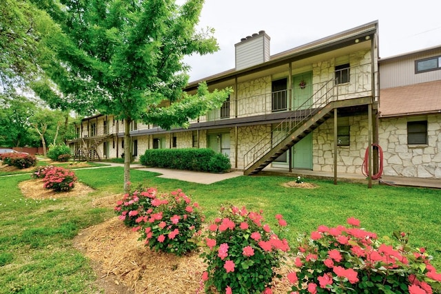 4307 S 1st St Unit 103, Austin, TX 78745 - back of house featuring stairs, stone siding, a chimney, and a yard