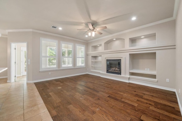 811 River Walk Trl, Georgetown, TX 78633 - unfurnished living room featuring ceiling fan, built in shelves, ornamental molding, recessed lighting, and a glass covered fireplace