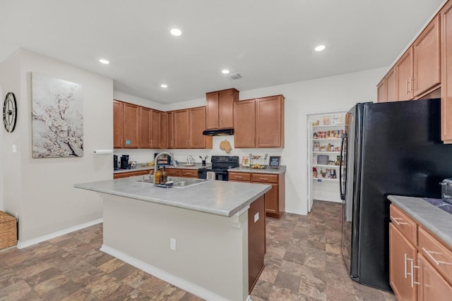 136 Everglades Ave, Taylor, TX 76574 - kitchen with black appliances, under cabinet range hood, a center island with sink, light countertops, and stone finish floors