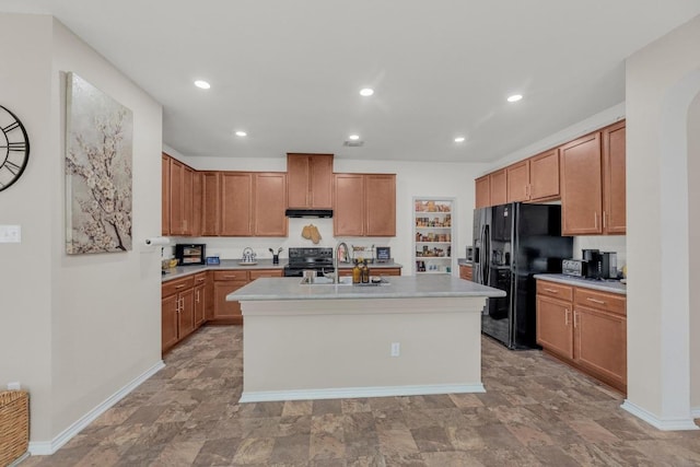 136 Everglades Ave, Taylor, TX 76574 - kitchen with electric range, black refrigerator with ice dispenser, light countertops, under cabinet range hood, and a kitchen island with sink