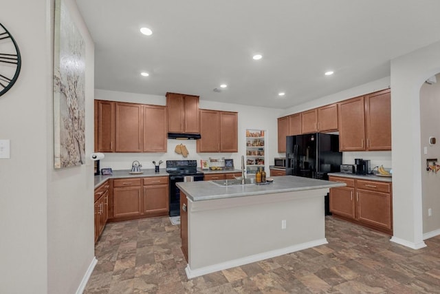 136 Everglades Ave, Taylor, TX 76574 - kitchen with black appliances, arched walkways, stone finish flooring, light countertops, and a kitchen island with sink