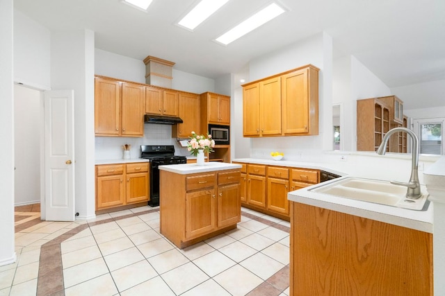 4917 Flaming Oak Cv, Austin, TX 78749 - kitchen with black range with gas stovetop, stainless steel microwave, under cabinet range hood, light tile patterned floors, and backsplash