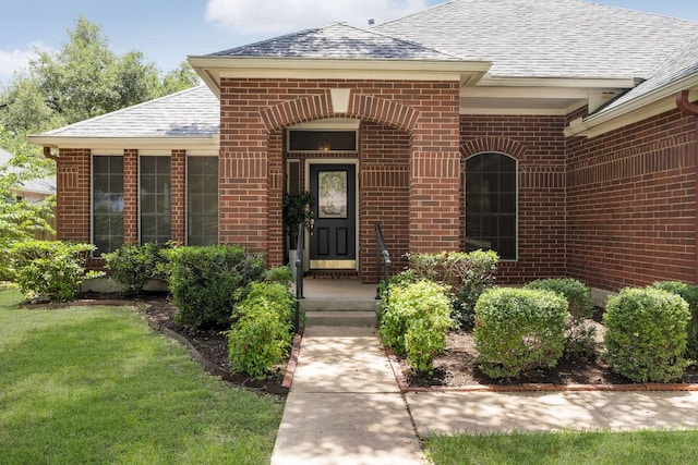 4917 Flaming Oak Cv, Austin, TX 78749 - view of exterior entry with a shingled roof, brick siding, and a lawn