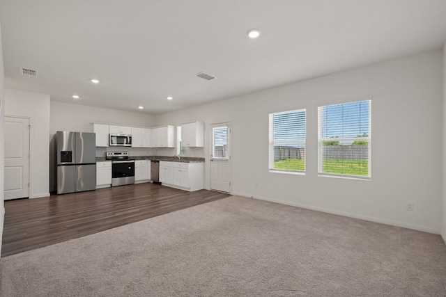 701 Redfish Ln, Hutto, TX 78634 - kitchen featuring stainless steel appliances, dark countertops, dark carpet, open floor plan, and white cabinets