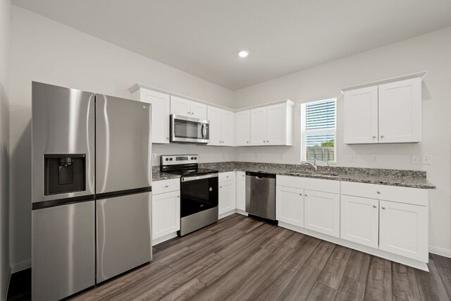 701 Redfish Ln, Hutto, TX 78634 - kitchen featuring stainless steel appliances, dark wood-style flooring, white cabinets, stone counters, and recessed lighting