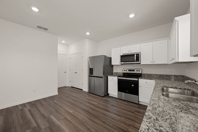 701 Redfish Ln, Hutto, TX 78634 - kitchen featuring appliances with stainless steel finishes, light stone countertops, white cabinetry, dark wood-style floors, and recessed lighting
