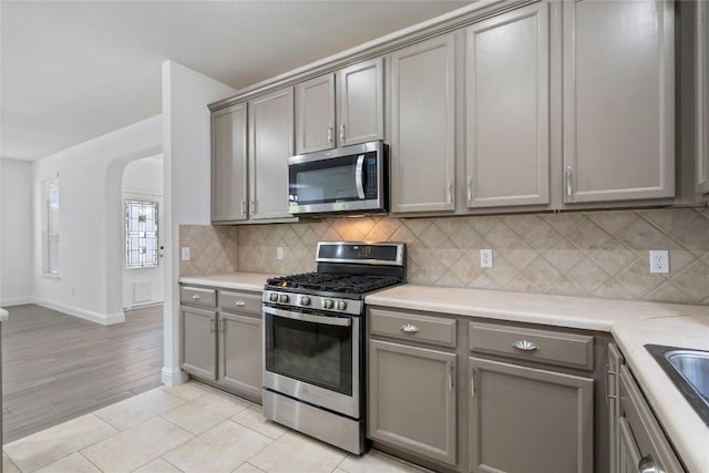 1102 Peyton Pl, Cedar Park, TX 78613 - kitchen featuring stainless steel appliances, gray cabinetry, arched walkways, and decorative backsplash