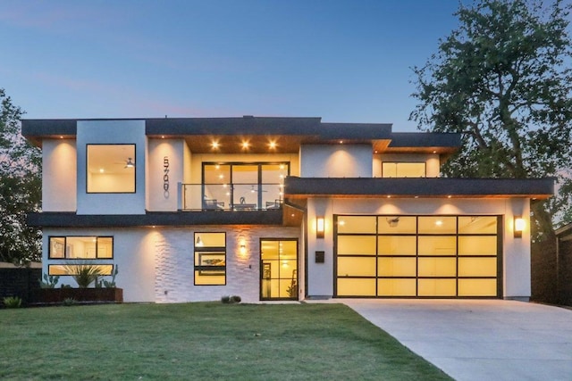 5700 Louise Ln, Austin, TX 78757 - contemporary house with stucco siding, concrete driveway, a front yard, a balcony, and an attached garage