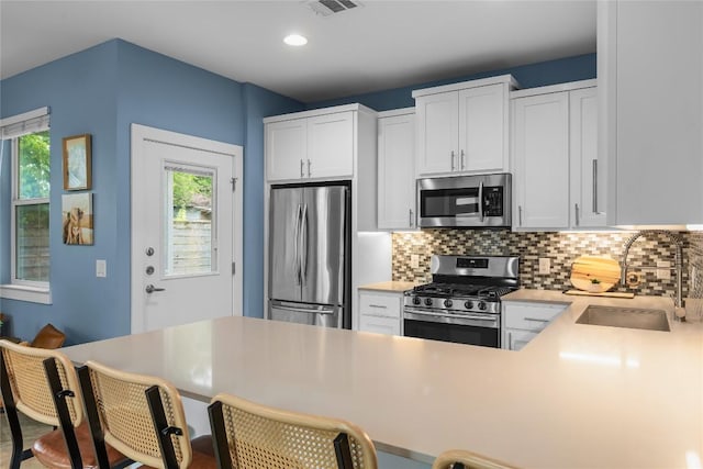 7606 Providence Ave Unit B, Austin, TX 78752 - kitchen with appliances with stainless steel finishes, backsplash, white cabinets, light countertops, and a breakfast bar