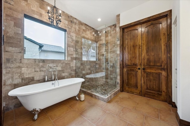 full bath featuring a soaking tub, a shower stall, tile walls, tile patterned flooring, and a chandelier