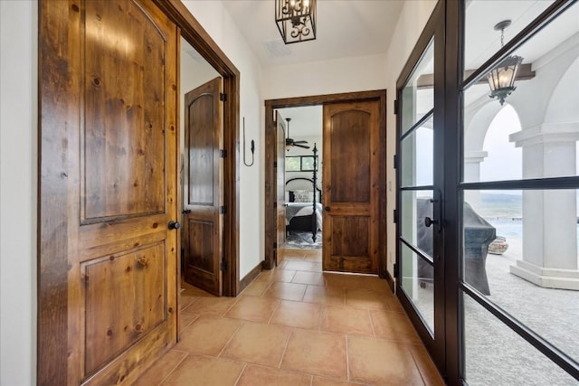 entryway with french doors, a chandelier, and arched walkways
