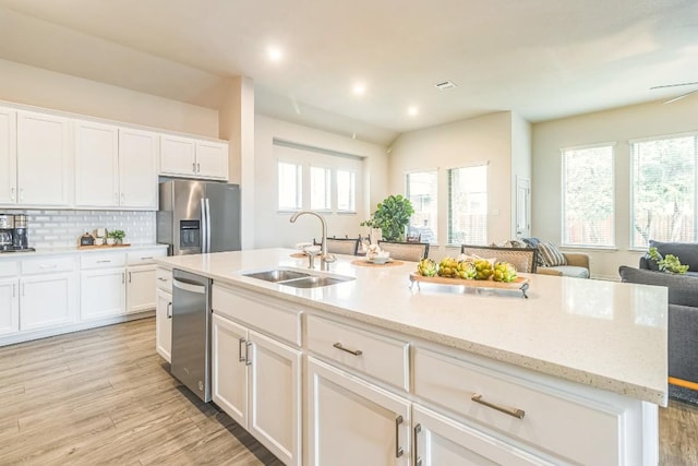 7901 Sunrise Ravine Pass, Lago Vista, TX 78645 - kitchen featuring appliances with stainless steel finishes, white cabinetry, tasteful backsplash, light wood-type flooring, and light stone counters
