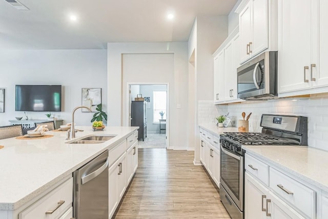 7901 Sunrise Ravine Pass, Lago Vista, TX 78645 - kitchen featuring appliances with stainless steel finishes, white cabinets, light wood finished floors, and decorative backsplash