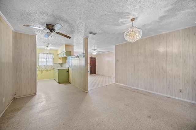 4705 Enchanted Ln, Austin, TX 78745 - unfurnished living room featuring tile patterned floors, a ceiling fan, a chandelier, wooden walls, and ornamental molding