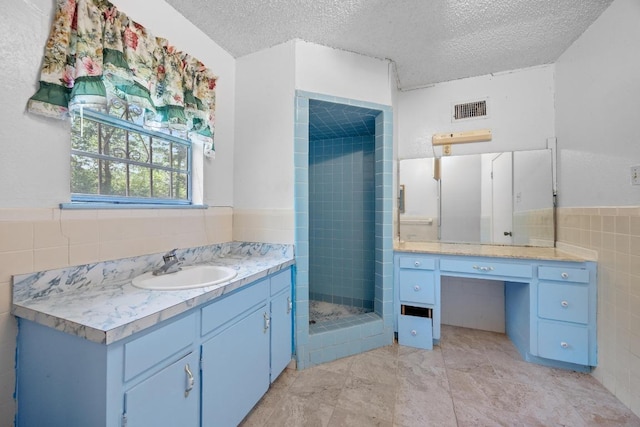 4705 Enchanted Ln, Austin, TX 78745 - bathroom with tile walls, vanity, a shower stall, a textured ceiling, and a wainscoted wall