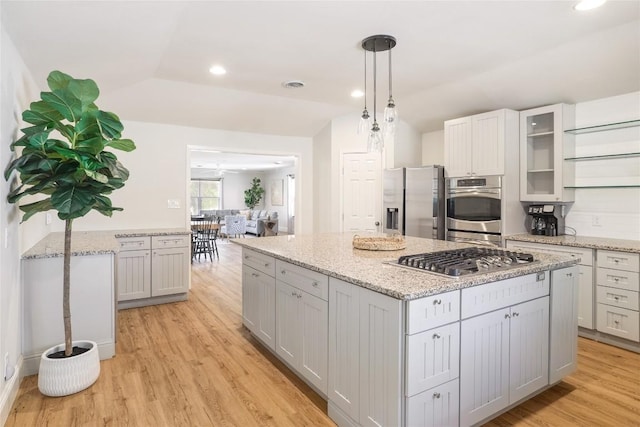2119 Rabb Rd, Austin, TX 78704 - kitchen featuring appliances with stainless steel finishes, a kitchen island, light wood finished floors, glass insert cabinets, and pendant lighting