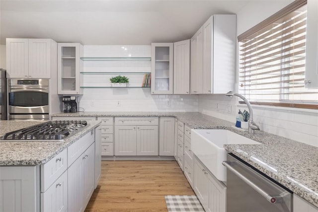 2119 Rabb Rd, Austin, TX 78704 - kitchen with appliances with stainless steel finishes, light wood-style floors, decorative backsplash, white cabinets, and light stone countertops
