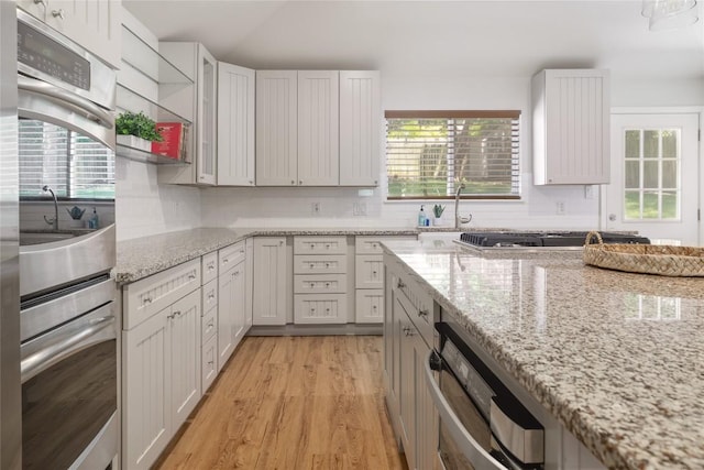 2119 Rabb Rd, Austin, TX 78704 - kitchen featuring double oven, light wood finished floors, light stone countertops, and backsplash