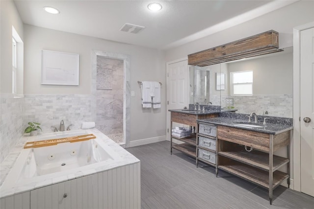 2119 Rabb Rd, Austin, TX 78704 - full bathroom featuring vanity, a jetted tub, walk in shower, tile walls, and recessed lighting