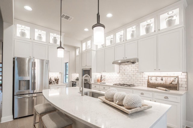 106 Double Eagle Ranch Dr, Cedar Creek, TX 78612 - kitchen with stainless steel appliances, an island with sink, under cabinet range hood, tasteful backsplash, and pendant lighting