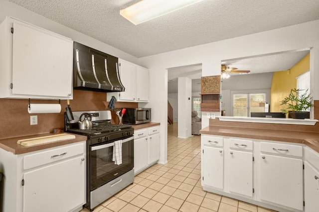 2810 Goldbridge Dr, Austin, TX 78745 - kitchen with appliances with stainless steel finishes, range hood, a textured ceiling, light tile patterned floors, and white cabinetry
