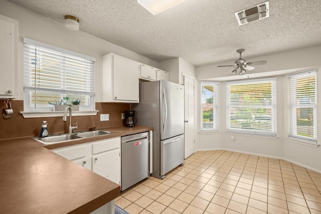 2810 Goldbridge Dr, Austin, TX 78745 - kitchen featuring stainless steel appliances, a ceiling fan, white cabinetry, light tile patterned flooring, and a textured ceiling